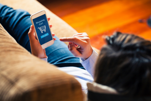 Woman laying on couch shopping on her phone.