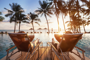 Two people sitting in beach chairs at sunset.