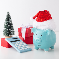 Piggy bank dressed in holiday hat with calculator and holiday presents